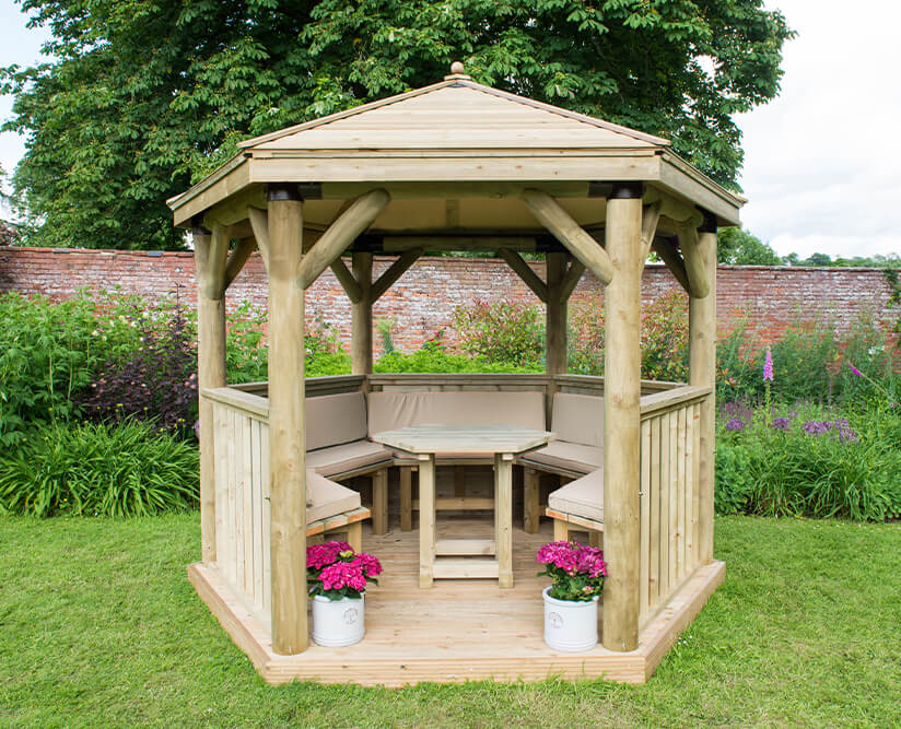 a luxurious wooden gazebo with integrated benches covered with brown cushions and a table in the middle