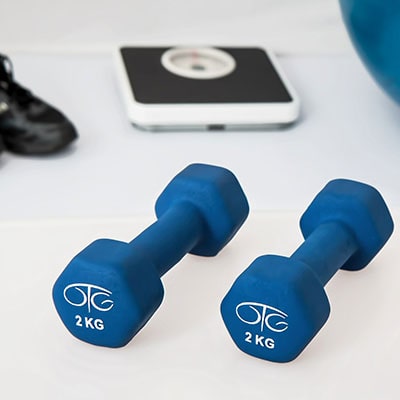 a photo of a white floor with a set of analogue scales and 2 blue 2KG dumbbells