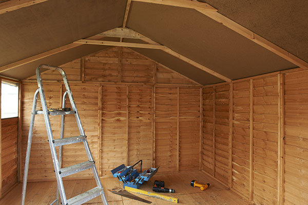 a wooden shed containing a step ladder and tools