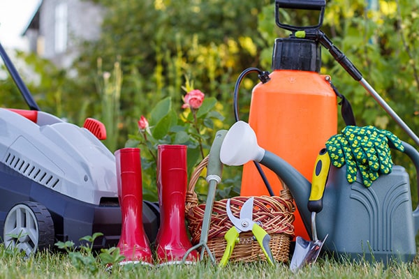 a lawnmower, red wellies, watering can and garden tools