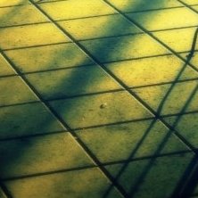 a close up of grey paving slabs in morning light with shadows