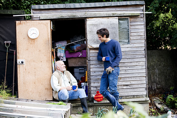 two gardeners chatting in front of a shed by an allotment