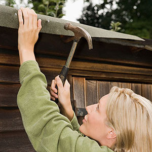 a woman fixing roof felt to a shed