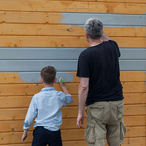 a man and a boy painting a shed