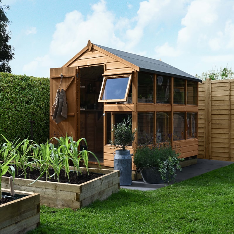 the 8x6 Forest Shiplap Potting Shed at the back of a garden