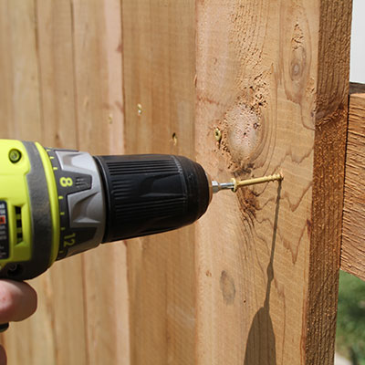 A screw being drilled into a fence panel