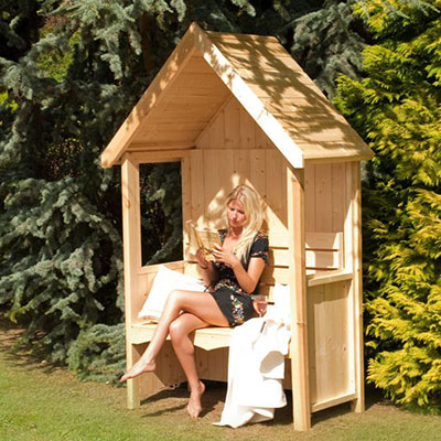 a woman sat reading on an arbour seat