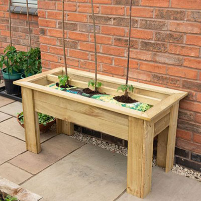 a wooden raised bed containing grow bags