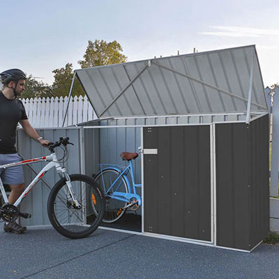 a man putting a bicycle into a grey metal bike shed