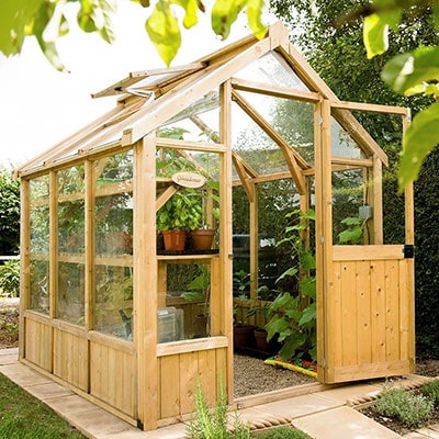 a wooden greenhouse with an open roof vent and sliding door