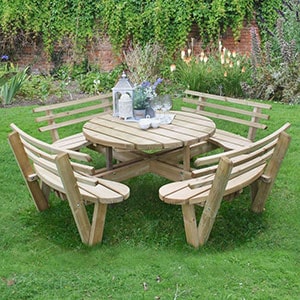 The Forest Circular Wooden Garden Picnic Table with Seat Backs, situated on a lawn and with a tea set on the table.