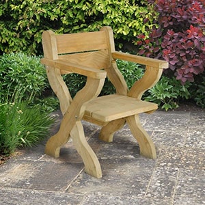The Forest Grizedale Wooden Garden Chair, sat on a patio, with shrubs in the background.