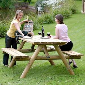 2 ladies with glasses of wine, sat in the garden at the Forest Picnic Table 4 Seater Round Legs