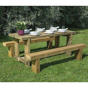 The Forest Sleeper Bench and Refectory Wooden Garden Table Set, with crockery on the table, and positioned on a lawn.