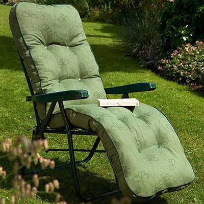a book resting on top of a green relaxer garden chair