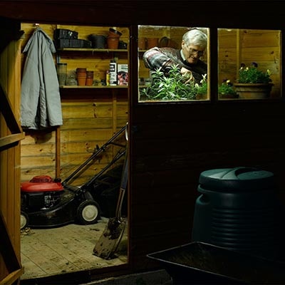 a man potting plants in a shed with solar lighting