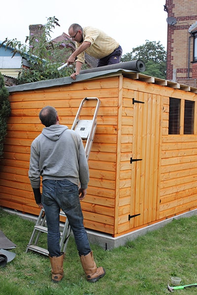men laying shed roof felt