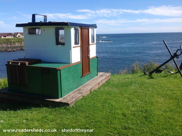Shed that looks a like a boat by a sea cliff top 